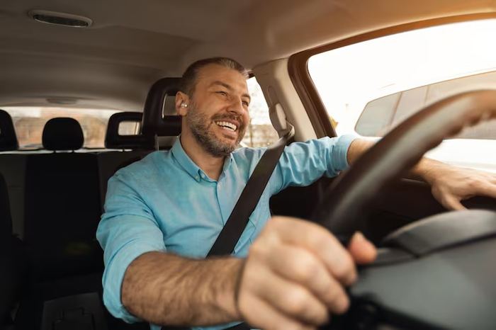 Homem sorrindo enquanto dirige o carro
